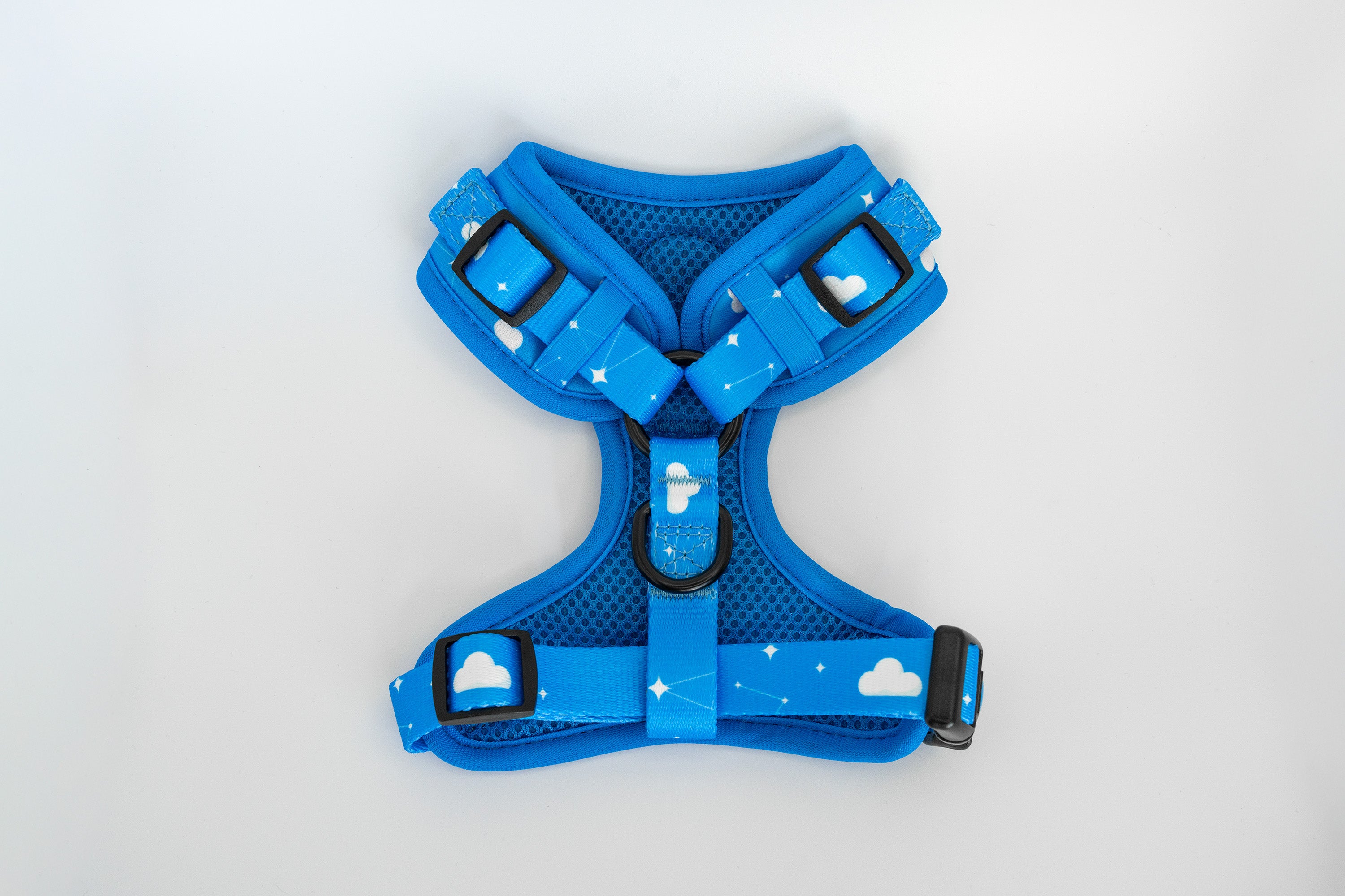 Blue dog harness with cloud designs on a light gray background